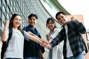 groupe de de bonne humeur Jeune asiatique entrepreneurs joindre mains ensemble à célébrer, excité Succès pour réalisations obtenu. premier cycle élèves célébrer Succès après fin projet, travail en équipe concept photo