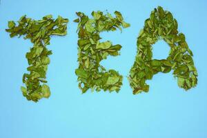 une inscription avec des lettres thé, séché à base de plantes feuilles de fruit des arbres sur turquoise photo