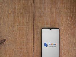 écran de lancement de l'application google translate avec logo sur l'affichage d'un smartphone mobile noir sur fond de bois photo