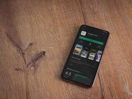 google lens app play store page sur l'affichage d'un smartphone mobile noir sur fond de bois
