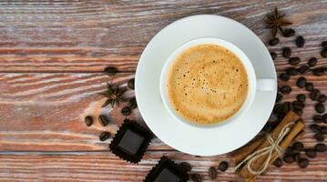 tasse de Frais parfumé cappuccino, Chocolat des sucreries et cannelle des bâtons sur une en bois Contexte. copie espace. fermer. Haut voir. sélectif se concentrer. photo