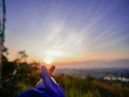 flou vue de le coucher du soleil ou lever du soleil dans le montagnes avec doigt l'amour photo