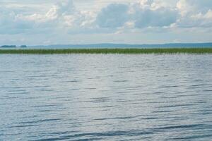 Naturel paysage aquatique, vaste peu profond Lac avec roseau banques sur une pluvieux journée photo