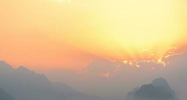 brillant le coucher du soleil ou lever du soleil ciel avec brumeux montagnes photo