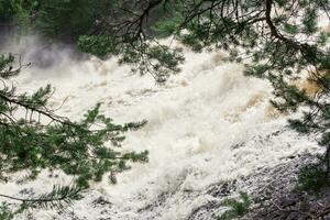 boueux turbulent courant en dessous de une Roche pendant haute l'eau photo