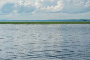 Naturel paysage, vaste peu profond Lac avec roseau banques sur une nuageux journée photo