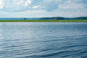 Naturel paysage, large Lac avec roseau banques et loin littoral photo