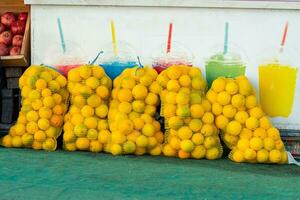 grand engrener Sacs de des oranges sont penché contre une mur avec une image de Frais jus dans une marché photo