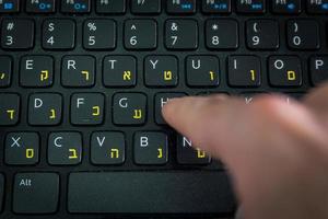 homme tapant sur un clavier avec des lettres en hébreu et en anglais photo