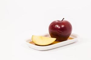 pomme rouge et tranche de pomme rouge sur plaque blanche avec du miel isolé sur fond blanc photo