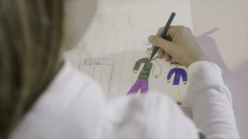 peu enfant dessine une crayon sur une feuille de papier. action. une Jeune fille dessine sur une feuille de papier. une cadeau pour maman photo