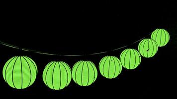 Halloween citrouille guirlande pendaison isolé sur une noir Contexte. conception. inhabituel vert lanternes dans une forme de une citrouille balancement dans le vent en dessous de le pluie gouttes. photo