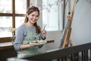 portrait de une Jeune femelle artiste travail sur un abstrait acrylique Toile La peinture dans un art La peinture studio. photo