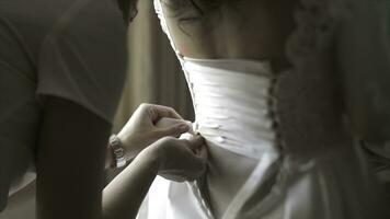 élégant magnifique demoiselles d'honneur portion magnifique brunette la mariée dans blanc robe avoir prêt pour mariage, Matin les préparatifs, femme en mettant sur robe. maman et demoiselle d'honneur, Aidez-moi à robe une mariage robe photo