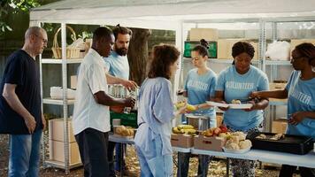 multiculturel bénévoles fournir gratuit, fraîchement préparé repas à pauvres et sans abri personnes. personnes de non lucratif organisation, en plein air portion nourriture à le nécessiteux et Moins privilégié. photo