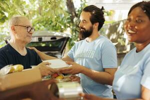 fermer de Multi-éthnique bénévoles, comprenant une souriant femme, distribuer des dons de nourriture à le nécessiteux, offre Aidez-moi et espérer à sans abri personnes. soins charité ouvriers aider le Moins privilégié. photo