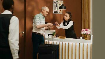 Sénior gars à de face bureau Faire vérifier dans routine dans coûteux cinq étoile Hôtel lobby. voyageur signature enregistrement formes à de face bureau, vérification pièce un service et commodités sur vacances voyage. photo