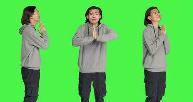la personne en gardant mains dans une prière à demander Jésus pour bien chance, sentiment religieux et prier contre écran vert isolé modèle. religieux asiatique gars agissant optimiste dans studio. photo