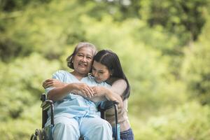 petite-fille parlant avec sa grand-mère assise sur un fauteuil roulant, concept joyeux, famille heureuse photo