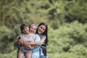 heureuse grand-mère en fauteuil roulant avec sa fille et son petit-enfant dans un parc, vie heureuse temps heureux. photo