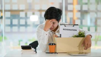 le concept de démission, employé masculin avec une boîte de rangement pour l'équipement après avoir démissionné, il s'inclina le visage stressé. photo