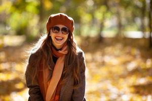 joyeuse jeune femme à lunettes de soleil et béret orange dans le parc d'automne photo