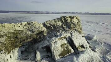 aérien vue de une énorme congelé Lac couvert par neige avec une falaise en hausse en haut par glace. agrafe. hiver paysage de le Naturel l'eau réservoir et une pierreux colline. photo