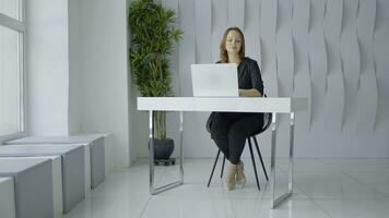 femme dans costume travail dans une moderne Bureau à le tableau. action. blanc des murs, vert plante et une table avec une ordinateur portable, minimaliste style. photo