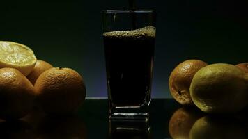 le concept de une barman. Stock clip.violet illuminé Contexte avec une grand spacieux verre dans lequel un soda est versé et le entier encore la vie est décoré avec lumière des oranges photo