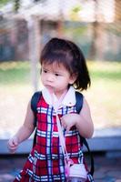 adorable petite fille a montré une expression qu'il se méfiait de quelque chose. portrait enfant porte une robe rouge. le tout-petit a 2 ans. photo