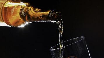 proche en haut de verser Bière de le verre marron bouteille dans le verre. vidéo. verser alcoolique boisson isolé sur noir arrière-plan, concept de faire la fête. photo