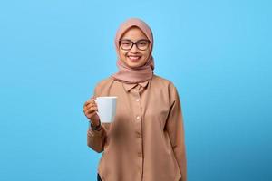 Portrait de bonheur jeune femme asiatique main tenir mug sur fond bleu photo
