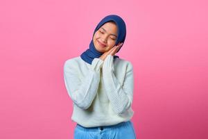 portrait de la belle jeune femme asiatique avec un geste de sommeil sur fond rose photo