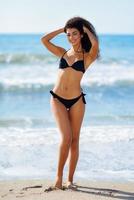 jeune femme arabe avec un beau corps en maillot de bain souriant sur une plage tropicale. photo