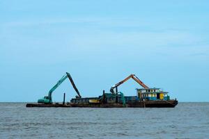 Machines sont dragage le sable dans le mer. photo