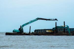 Machines sont dragage le sable dans le mer. photo