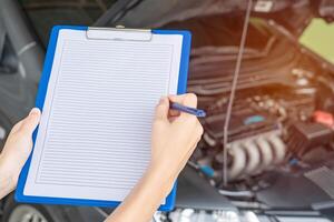 des employés femmes de le voiture un service centre vérification liste sur le papier Remarque pour entretien et un service voiture photo