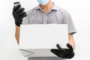 Accueil livraison homme à la recherche téléphone intelligent vérifier Les données avant livraison achats boîte portant gants et protecteur masque dans blanc ciment mur photo