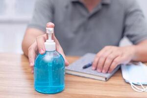 main une homme presse main désinfecter bouteille et porter une masque pour protection et quarantaine pandémie virus dans travail travail de Accueil photo