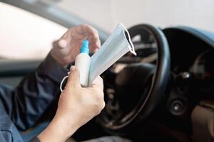 proche en haut main une homme tenir masque et de l'alcool vaporisateur pour prévenir germes et virus dans chaque journée et dans côté voiture dans Contexte photo