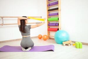 Jeune femme est Faire gymnastique dans salle de sport. en bonne santé mode de vie. élastique bande photo