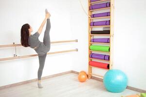 Jeune femme est Faire gymnastique dans salle de sport. en bonne santé mode de vie. en bois balustrade photo