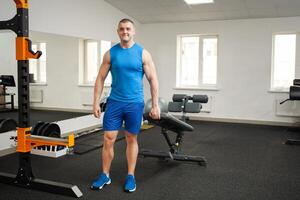 une mignonne Jeune entraîneur inspire confiance, une des sports corps, pose sur le simulateur dans salle de sport. musclé corps, une homme enseigne, encadrement, physique activité, poids perte programme. copie espace photo