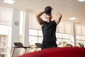 musclé entraîneur jette le Balle sur une trampoline, une muscle entraîneur, une salle de sport. portrait de une magnifique homme, encadrement, individuel poids perte et des sports cours. simulateur photo