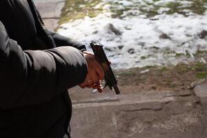 une homme recharge une pistolet. en dehors de le porte, tournage gamme. meurtre, danger, armes à feu. neige sur le sol photo