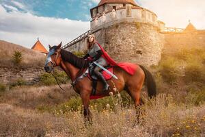 une magnifique fille dans le costume de le guerrier reine. une femme sur à cheval avec une épée dans sa main. photo