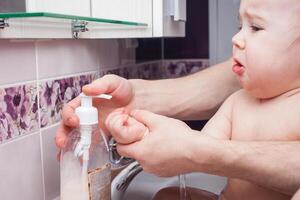 enfant lavages mains dans couler. jet de l'eau de robinet. désinfection de mains avec l'eau. photo