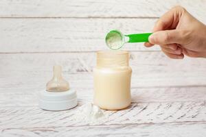 bébé bouteille avec Lait formule sur une blanc en bois Contexte photo