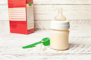 bébé bouteille avec Lait formule sur une blanc en bois Contexte photo