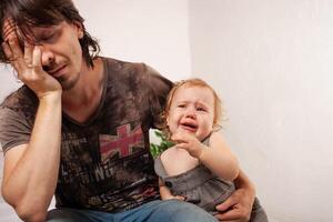 le enfant est en hurlant, hystérique. une fatigué papa ne fait pas vouloir à entendre le bébé. le parent est irrité, fatigué, veut à prendre une Pause de le sien fille. enfants hystérie. photo